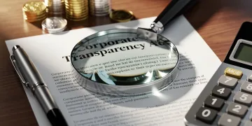 Magnifying glass over Corporate Transparency Act document, symbolizing compliance scrutiny.